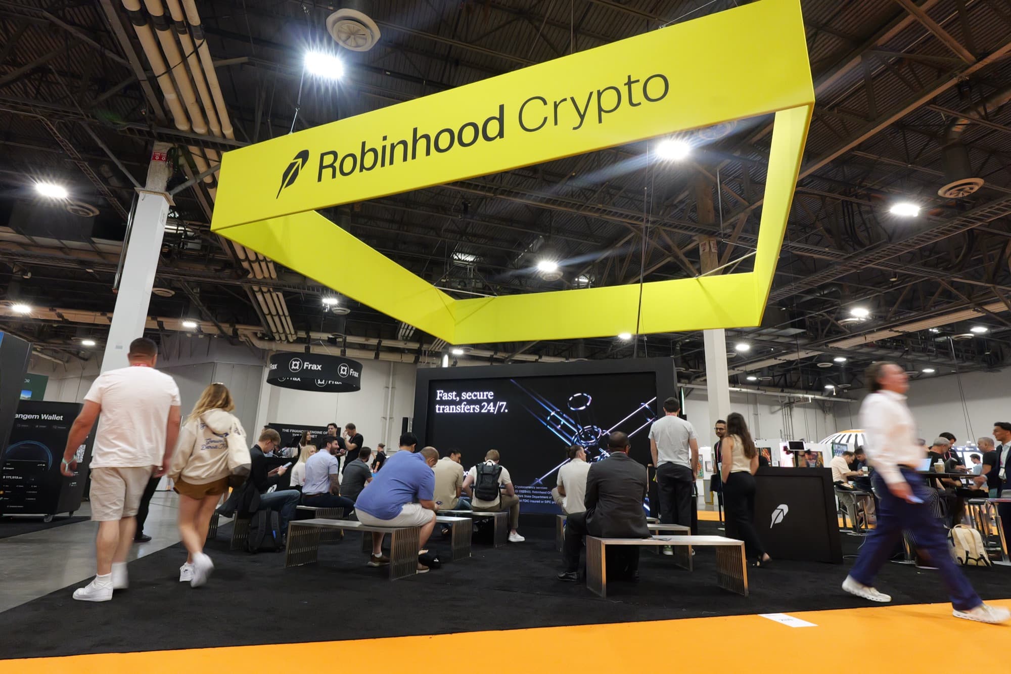 A yellow Robinhood Crypto sign suspended over an expo floor booth